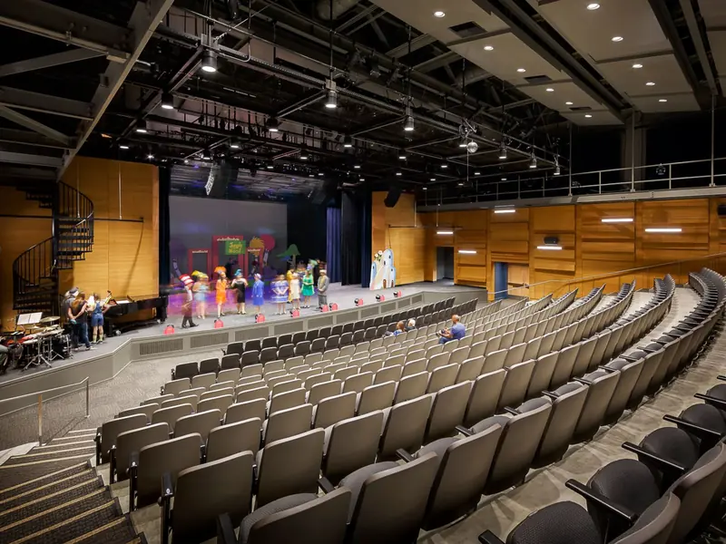 Young performers on a school auditorium stage, the house lights low.
